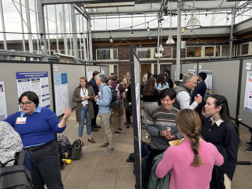 Many people looking at and discussing posters on rows of bulletin boards in an atrium