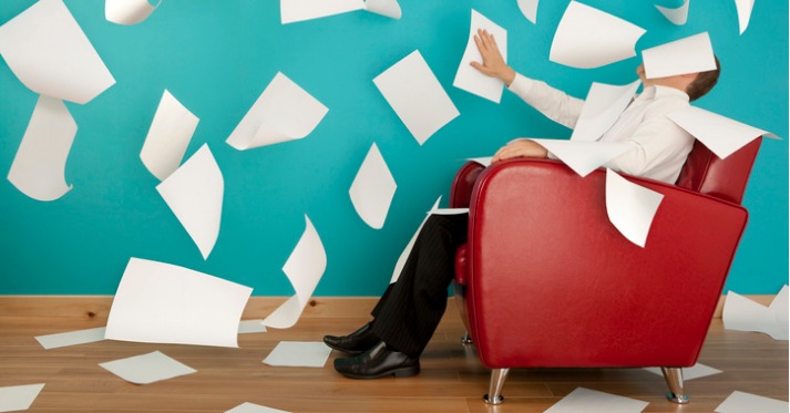 man in chair with papers flying all around him