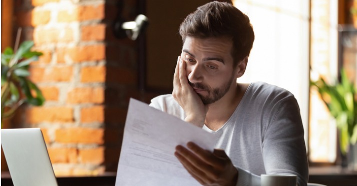 a concerned looking man reading a piece of paper