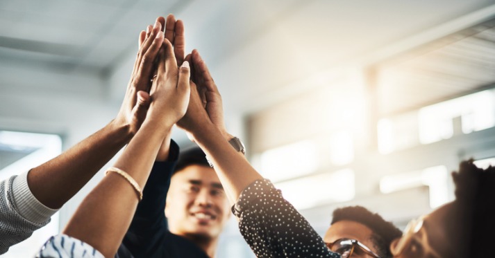 a group of unrecognizable people high fiving in an office